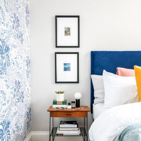 חדר שינה עם קירות לבנים וראש מיטה כחול