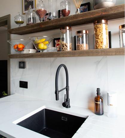 Spülbeckenbereich in der Küche mit weißen Wandfliesen und Holzregalen