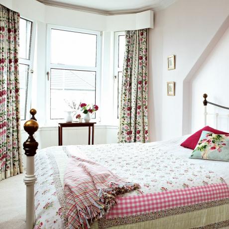 Dormitor alb cu bovindou, perdele florale și pat din fier forjat