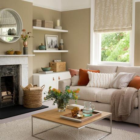 غرفة معيشة باللون البيج مع أريكة محايدة ووسائد برتقالية