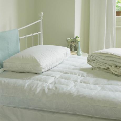 Säng utan sängkläder med en kudde ovanpå