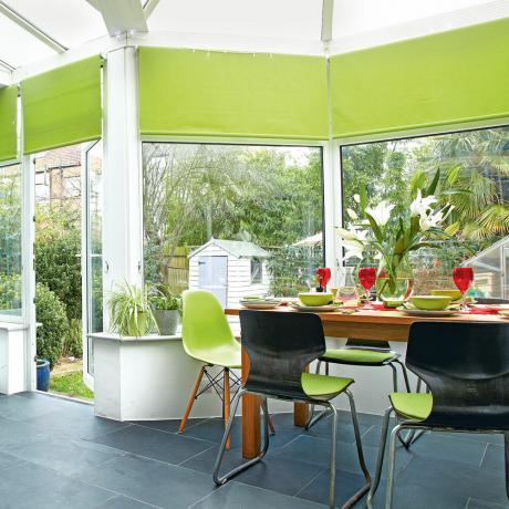 jardim de inverno cortinas verdes e mesa de jantar com cadeiras verdes