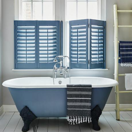 Vitt badrum med blått fristående klobadkar och matchande caféluckor - Shutterly Fabulous