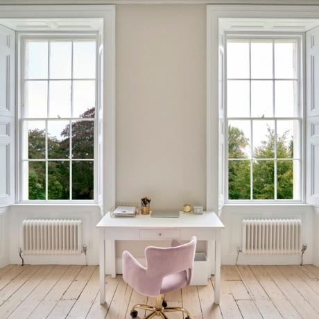 หน้าต่างบานกระทุ้งขนาดใหญ่ 2 บานในโทนสีครีมแบบบ้านย้อนยุค พร้อมโต๊ะสีขาวและเก้าอี้สีชมพู