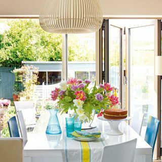 Ljus matsal med tvåfaldiga dörrar och utsikt över trädgården
