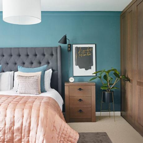 Blågrönt sovrum med grå sänggavel och rosa plagg