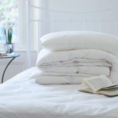 Übereinander gestapelte weiße Bettdecken auf dem Bett
