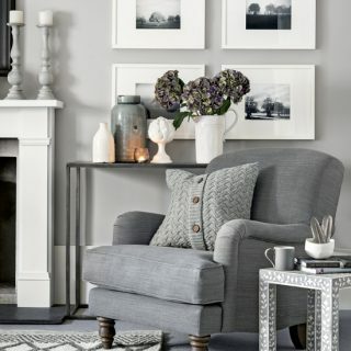 Sala de estar cálida de color gris claro con sillón acogedor y cojín de punto