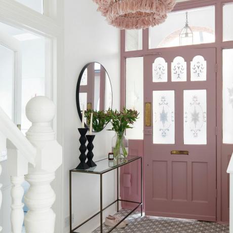Biały korytarz z frontowymi drzwiami w stylu epoki pomalowanymi na różowo