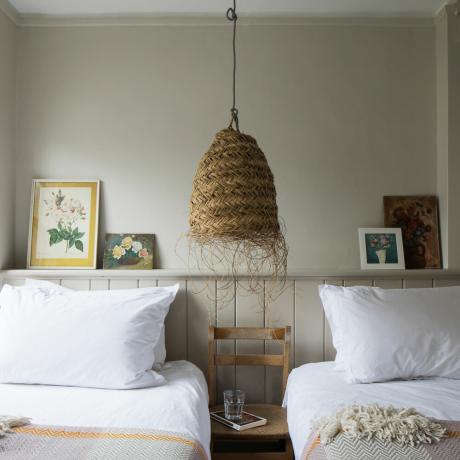 slaapkamer met twee eenpersoonsbedden met lambrisering en natuurlijke plafondhanger
