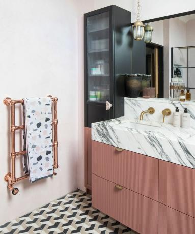 Zwarte en roze badkamer met tegelvloer met patroon en hoge ikea-kast veranderd in badkameropslag