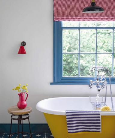 Salle de bain avec cadres de fenêtre peints en bleu et baignoire peinte en jaune