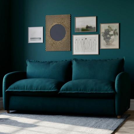 Blågrønn sofa mot blågrønn vegg med galleriutstilling