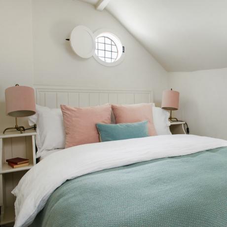 sovrum med blått och rosa sängkläder och rosa lampskärmar