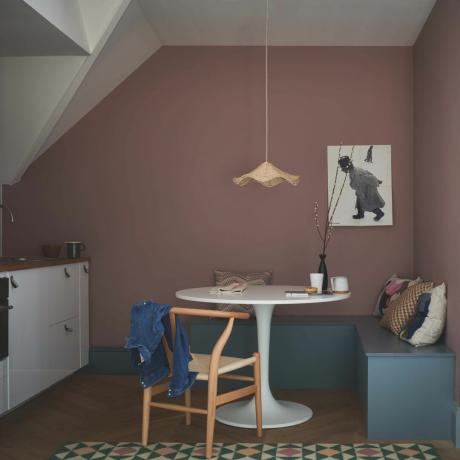 مطبخ مع مقاعد بوكس ​​أزرق وطاولة مستديرة بيضاء وجدران وردية