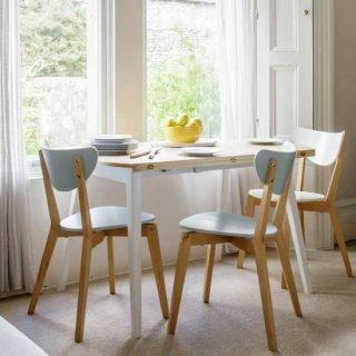 Salle à manger blanche avec table en demi-lune et chaises pastel
