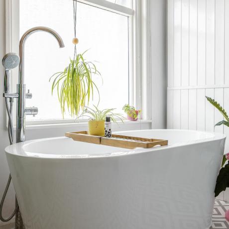 Valkoinen kylpyhuone pystysuunnassa laatoilla, ikkunalla ja kylpyammeella