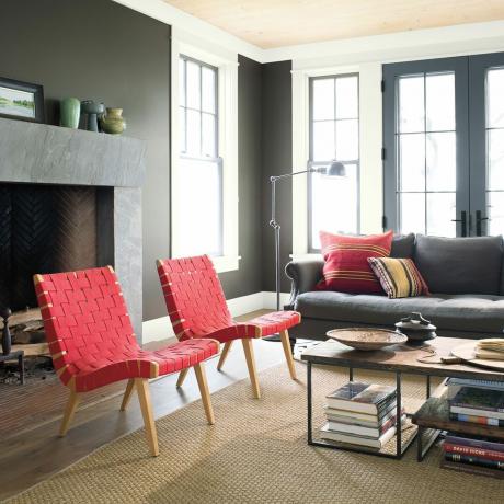 grijze woonkamer met groot raam en rode stoelen