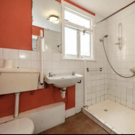 オレンジ色の壁とパイプが見える古いバスルーム