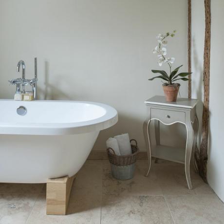 Weiße freistehende Badewanne im Cottage-Badezimmer mit kleinem grau lackierten Beistelltisch