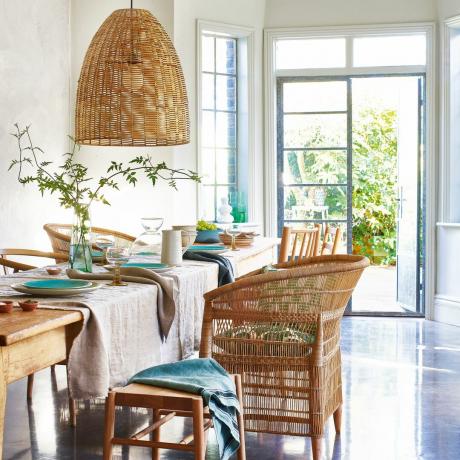 שולחן ערוך במצעים פסטליים, עם כיסאות גן ראטן ודלתות צרפתיות פתוחות