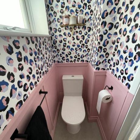 lille toilet i underetagen med lyserøde vægpaneler og tapet med dyreprint