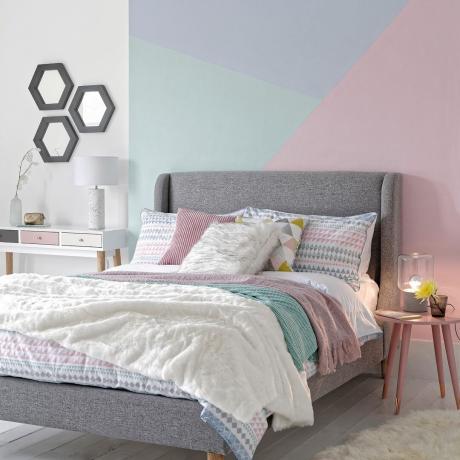 غرفة نوم مع جدار باللونين الأزرق والوردي وسرير أبيض
