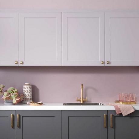o bucătărie roz cu dulapuri gri, suprafață de marmură și accesorii roz