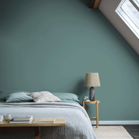 Grönt sovrum med dubbelsäng och sängbord