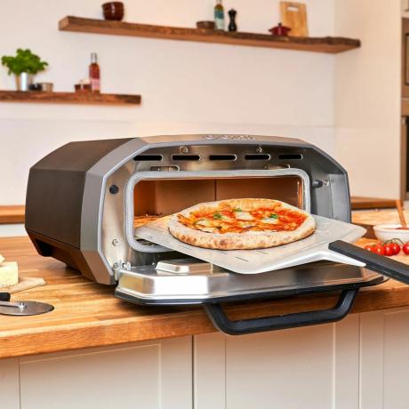 Der Ooni Volt 12 (ein Pizzaofen für den Innen- und Außenbereich) in einer Küche, der zum Backen einer Pizza verwendet wird