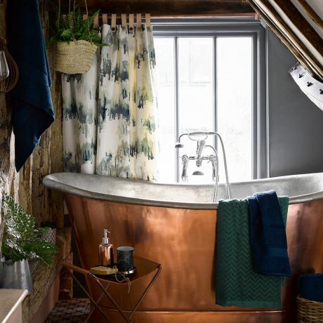 Πολυτελές εξοχικό μπάνιο με μπανιέρα χαλκού και φυτά εσωτερικού χώρου