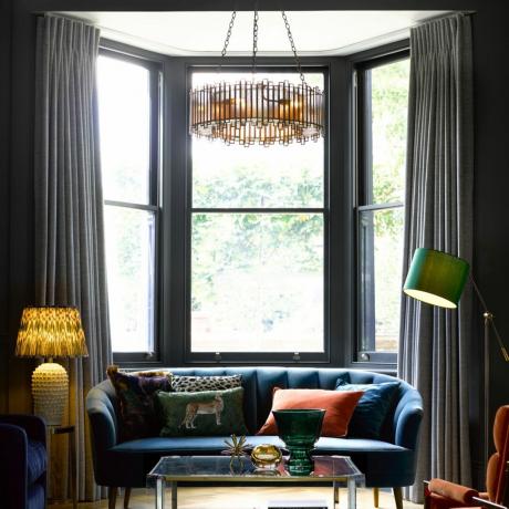 sala de estar con gran ventanal y sofá y lámpara de mesa, lámpara de pie y lámpara de araña grande