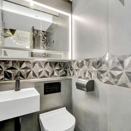 Сіра ванна кімната з дзеркалами та візерунчастою плиткою