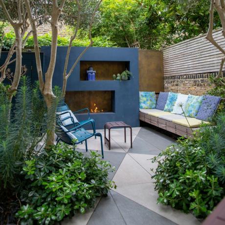 blåmalet have med tofarvet terrassegulv og udendørs pejs