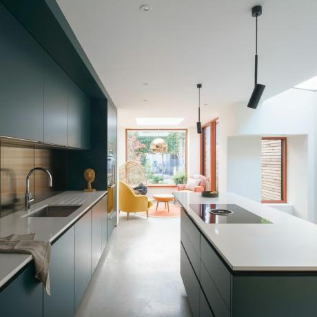 moderne grønt kjøkken med kjøkkenøy og sittegruppe ved siden av et vindu
