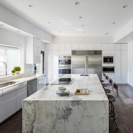 Vitt modernt kök med en marmorö