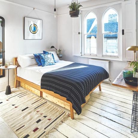 Schlafzimmer mit marineblauen Akzenten – marineblauer Überwurf und Kissen, strukturierter Teppich