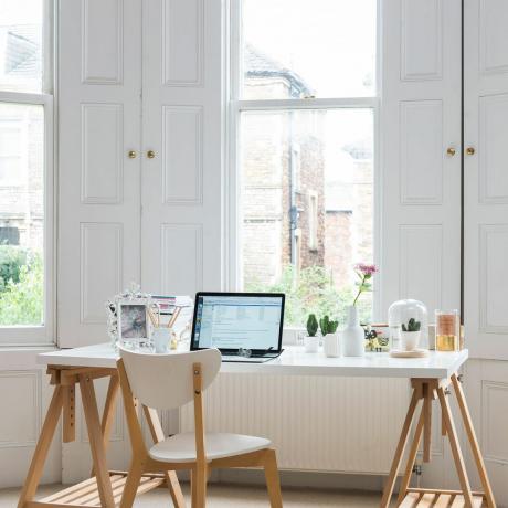 Zona de birou în fața ferestrelor cu obloane din lemn