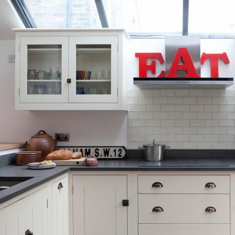 kreminė virtuvė su stoglangiais ir raudonomis dekoratyvinėmis raidėmis EAT