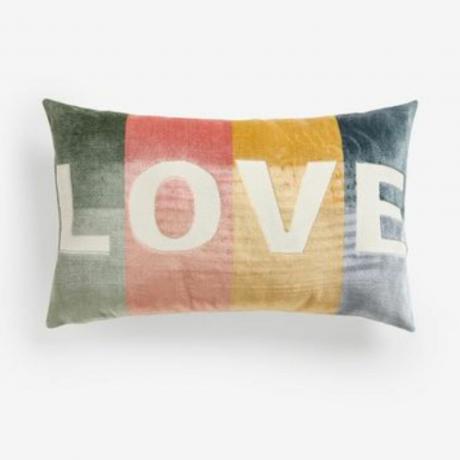 Stačiakampė minkštų pastelinių atspalvių pagalvėlė, ant kurios baltai išsiuvinėtas žodis LOVE