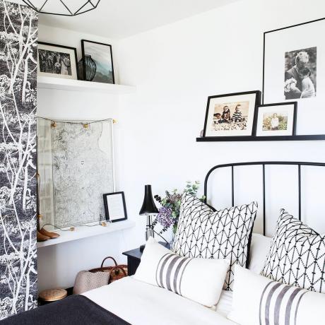 Hvidt soveværelse med kort på væg og sort seng