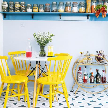 Κουζίνα με μπλε ράφι, στρογγυλό τραπέζι και κίτρινες καρέκλες τραπεζαρίας