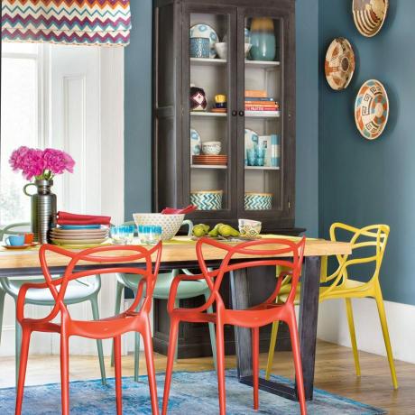 Donkerblauwe eetkamer met eigentijdse stoelen