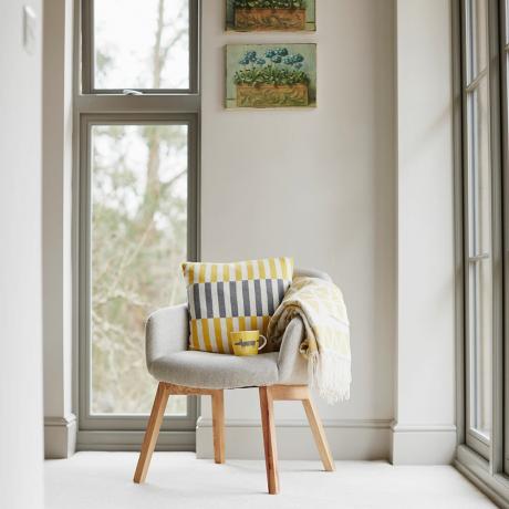 Una silla sentada junto a una ventana con marcos de madera.