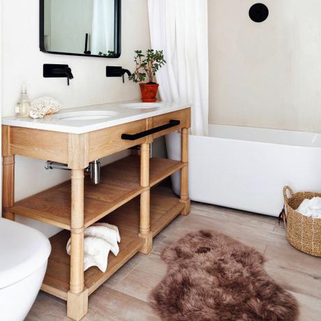 Vitt badrum med dubbla handfat och brun matta