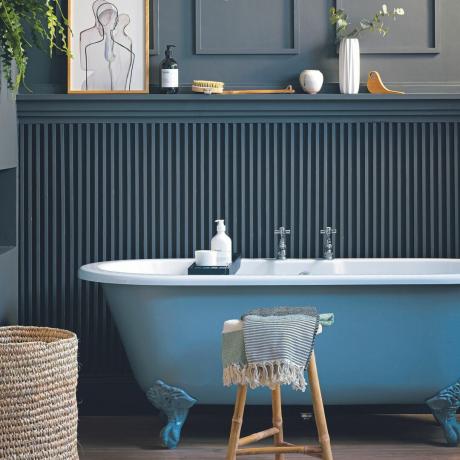 Duvar panelleri ve mavi küveti olan lacivert banyo.