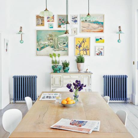 Modré maľované radiátory v jedálni veľkého domu s galériovou stenou a veľkým dreveným jedálenským stolom