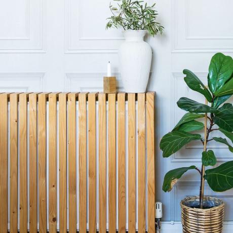 Copertura del radiatore in legno fai-da-te sopra il radiatore nel soggiorno con pareti rivestite di pannelli