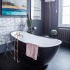 Koksgrå badrumsmakeover med svart badkar med toppar och konstiga konstverk