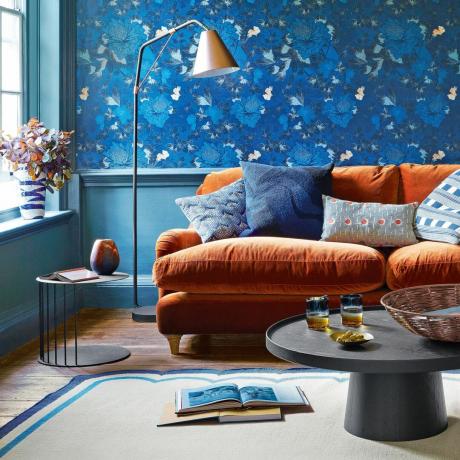 ruang tamu dengan wallpaper biru dan sofa oranye
